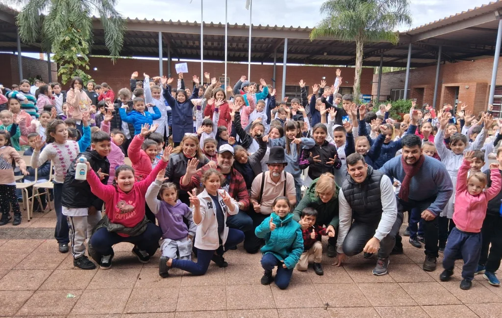 Equipo de Gurises Felices y multitud de niños de escuelas de Puerto Iguazú saludan felices a la cámara.