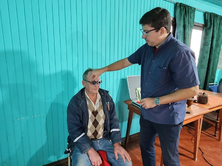 Oftalmólogo chequea graduación de lentes a un vecino en Colonia Aurora.