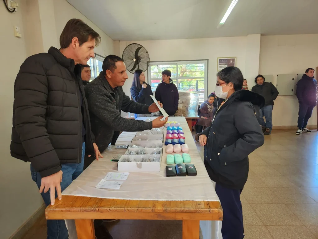 Héctor Decut junto a un colaborador de Mirar Mejor entregan anteojos a una vecina de Gobernador Roca.