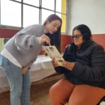 Oftalmologa ayuda a una vecina a leer con lentes de prueba. Mirar Mejor en Guaraní.