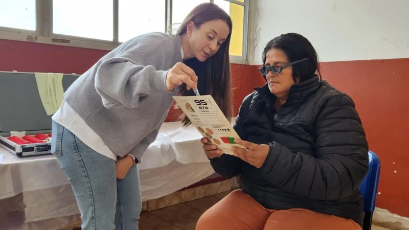 Oftalmologa ayuda a una vecina a leer con lentes de prueba. Mirar Mejor en Guaraní.