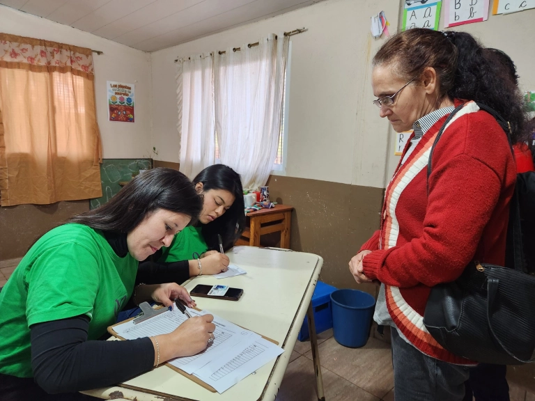 Una vecina completa un trámite con la ayuda de dos colaboradoras del operativo.