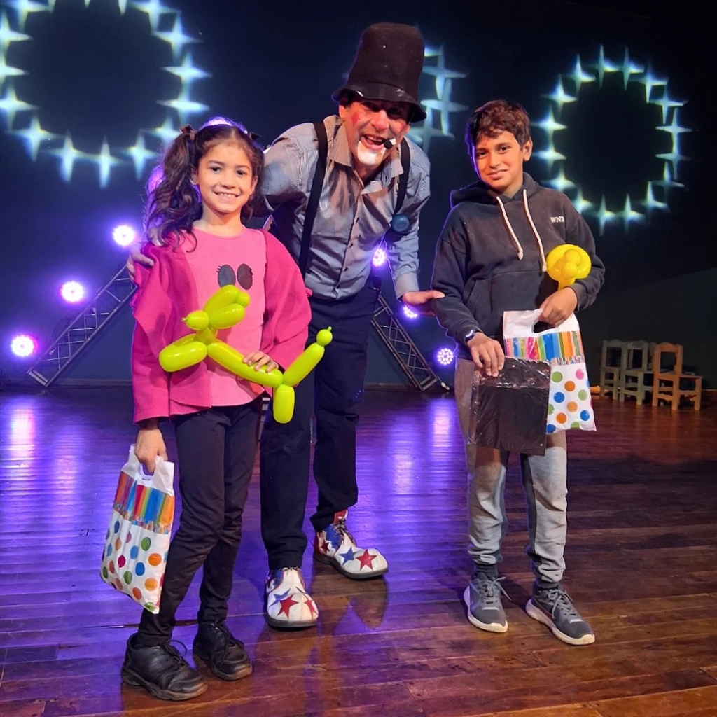 Dos niños felices con sus obsequios, junto a Poca Sopa.
