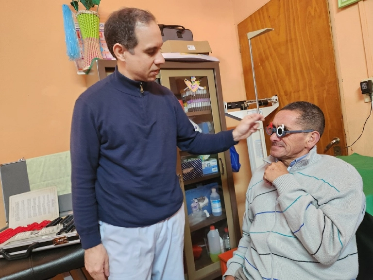Oftalmólogo controla la vista de un vecino usando lentes graduados.