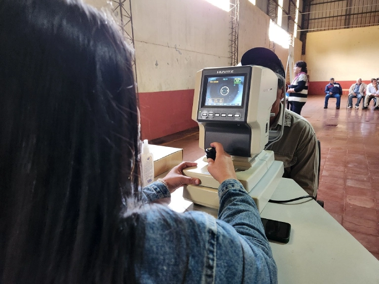 Oftalmóloga usa un auto refractómetro para controlar la vista de un vecino.