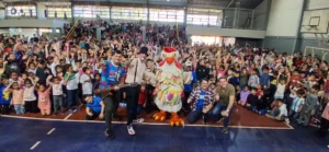 Equipo de Gurises Felices y una multitud de niños saludan felices a la cámara.
