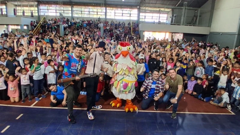 Equipo de Gurises Felices y una multitud de niños saludan felices a la cámara.
