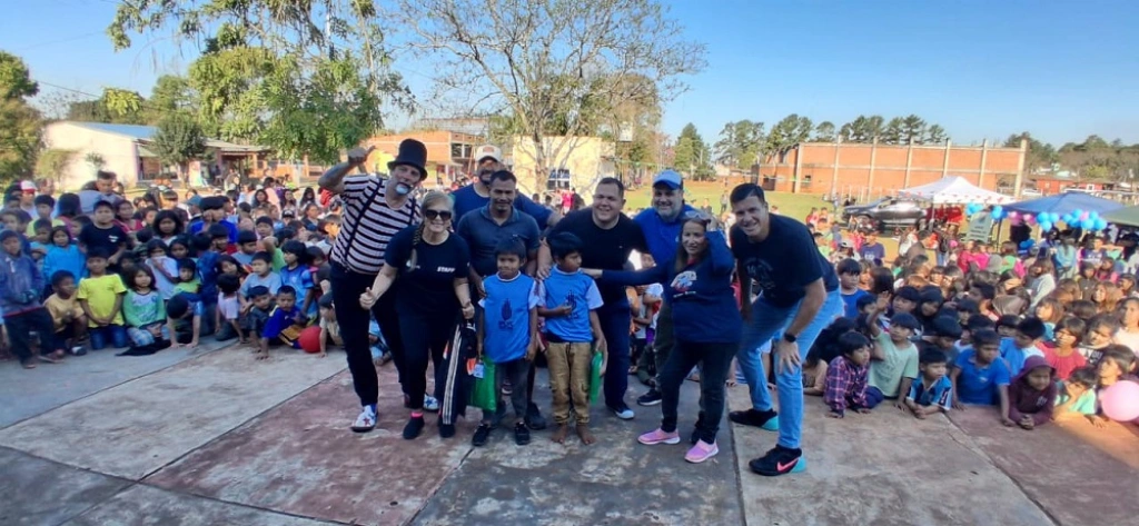 Dos niños con sus obsequios junto al equipo de Gurises y multitud de niños en san Ignacio.