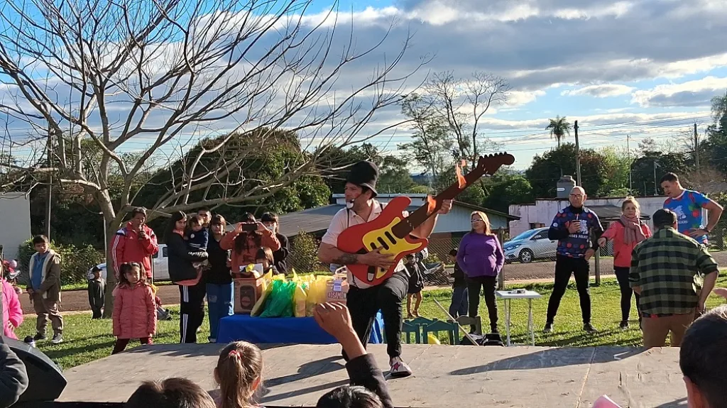 Poca Sopa divierte a los niños de Gobernador Roca tocando una guitarra.