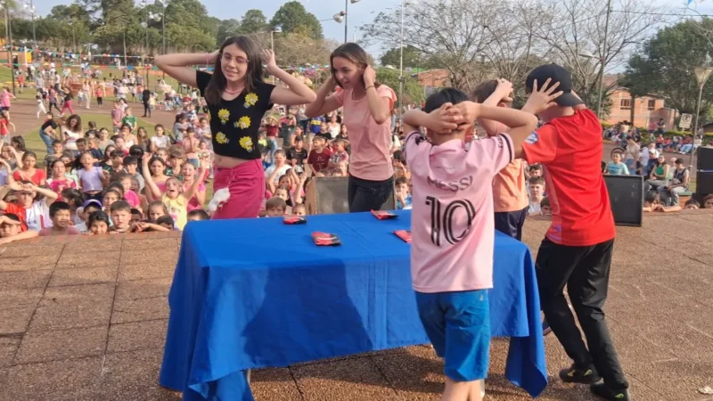 Niños realizan un juego alrededor de una mesa. Gurises Felices en 25 De Mayo.