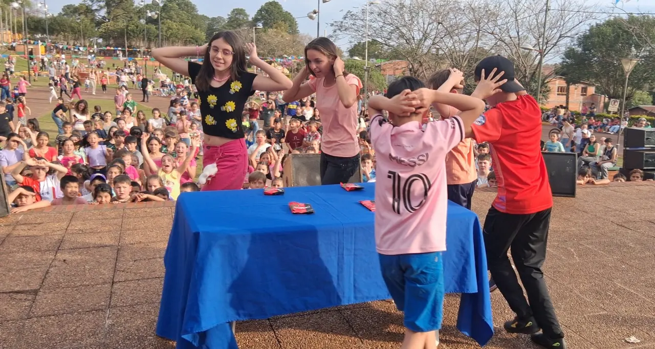 Niños realizan un juego alrededor de una mesa. Gurises Felices en 25 De Mayo.