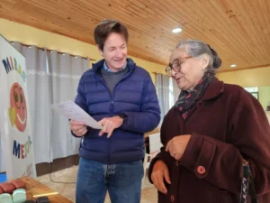 Héctor Decut le toma lectura a una señora mayor muy sonriente con sus nuevos lentes. Mirar Mejor - San Martín.
