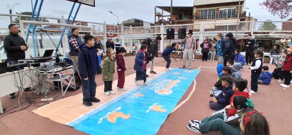 Grupo de niños participan de un juego en el playón del Mercado Modelo de Posadas dirigidos por Poca Sopa.