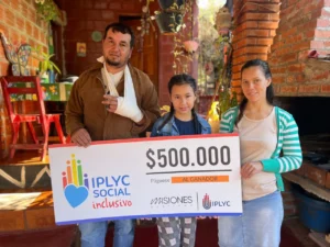 Víctor junto a su hija y esposa, sonríen con su cheque. Usará el dinero del premio para los gastos diarios de la casa.