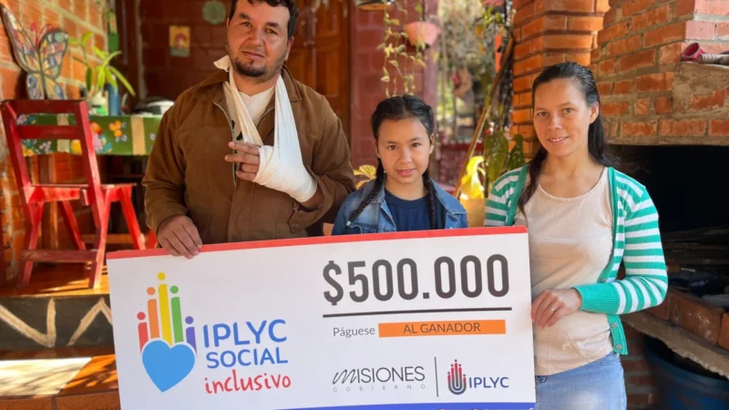 Víctor junto a su hija y esposa, sonríen con su cheque. Usará el dinero del premio para los gastos diarios de la casa.