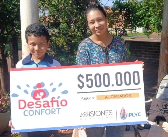 Graciela y su hijo felices con su cheque. Usarán el dinero para avanzar con la construcción de su casa.