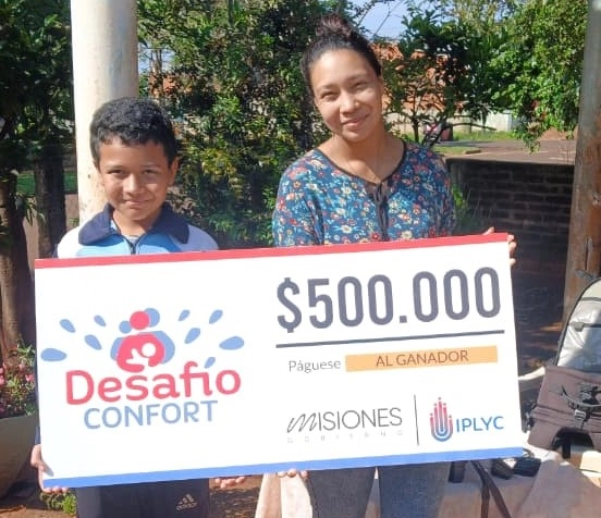 Graciela y su hijo felices con su cheque. Usarán el dinero para avanzar con la construcción de su casa.