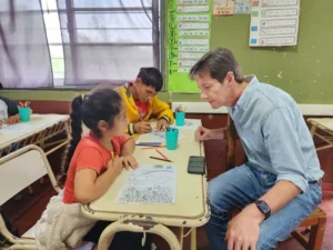 Héctor Decut charla con una niña que se entretiene pintando durante el operativo Estamos con Vos en General Urquiza.
