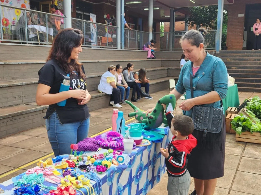 Un pequeño elije un juguete junto a su mamá, de una feriante que vende artesanías manuales.