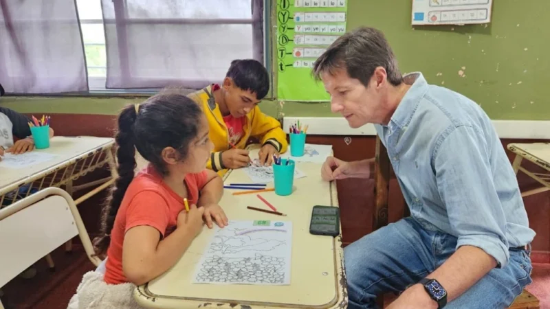 Héctor Decut charla con una niña que se entretiene pintando durante el operativo Estamos con Vos en General Urquiza.
