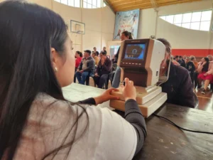 Oftalmóloga controla la vista de una vecina con un autorefractómetro. Mirar Mejor atendió la salud visual en 25 De Mayo.