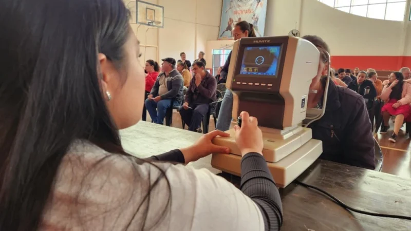 Oftalmóloga controla la vista de una vecina con un autorefractómetro. Mirar Mejor atendió la salud visual en 25 De Mayo.
