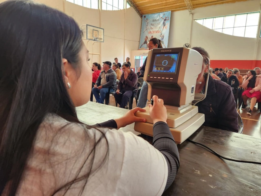 Oftalmóloga controla la vista de una vecina con un autorefractómetro. Mirar Mejor atendió la salud visual en 25 De Mayo.