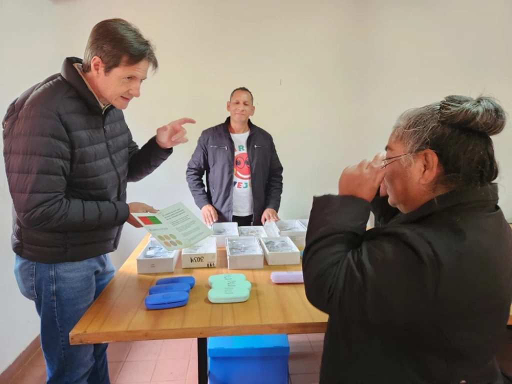 Héctor Decut ayuda a leer un texto de prueba a una vecina con sus nuevos anteojos.