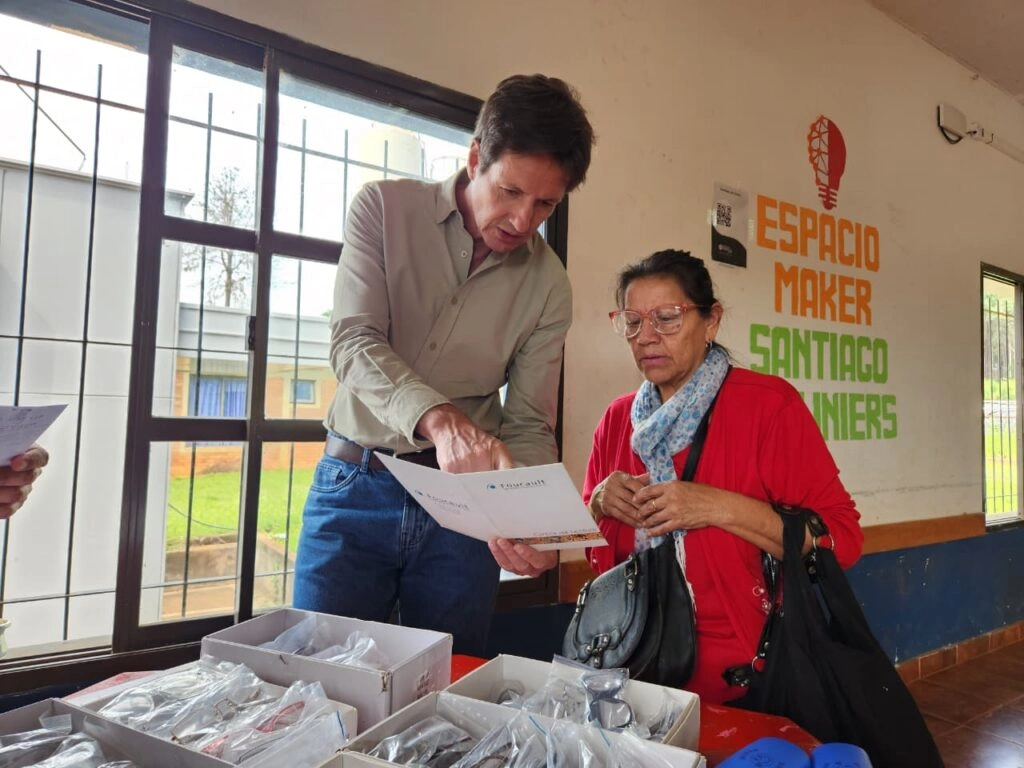 Vecina lee un texto con sus nuevos anteojos asistida por Héctor Decut.