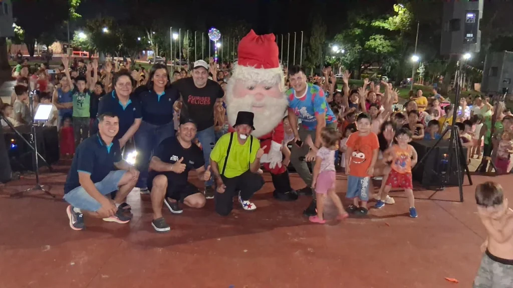 Equipo de Gurises y Papá Noel, junto a los niños saludan felices sobre el escenario.