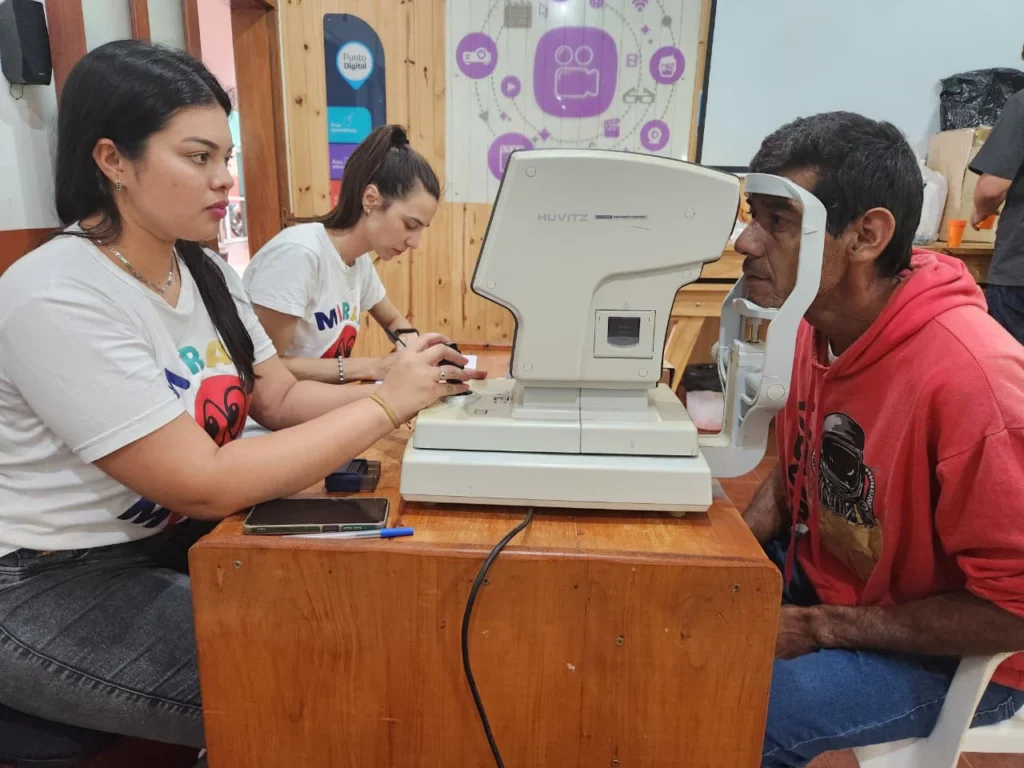 Oftalmóloga mide la graduación de los ojos de un vecino con un autorefractómetro.