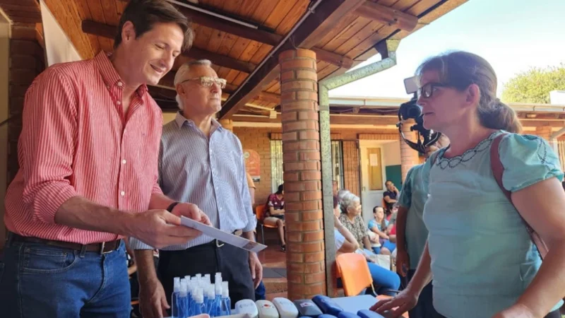 Héctor Decut ayuda a leer un texto a una vecina de Capoví con sus nuevos anteojos. Operativo de salud visual Mirar Mejor.