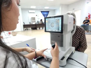 Oftalmóloga revisa los ojos de una vecina con un autorefractómetro. Mirar Mejor - Loreto.
