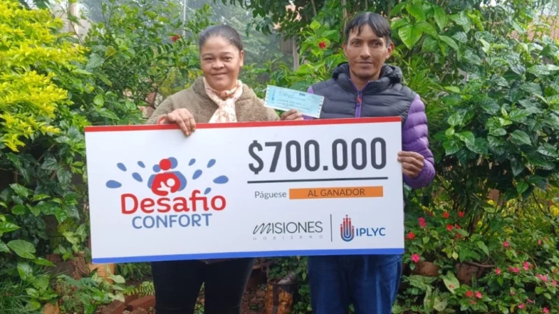 Raúl y su esposa sonríen con su cheque. Comprará materiales para arreglar su casa.