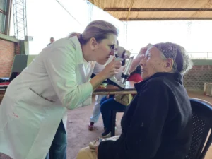 Oftalmóloga usa un tonómetro para medir la presión ocular de una vecina mayor de Alem.