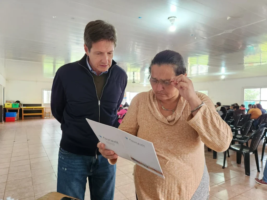 Señora lee un texto con sus nuevos anteojos de Mirar Mejor junto a Héctor Decut.