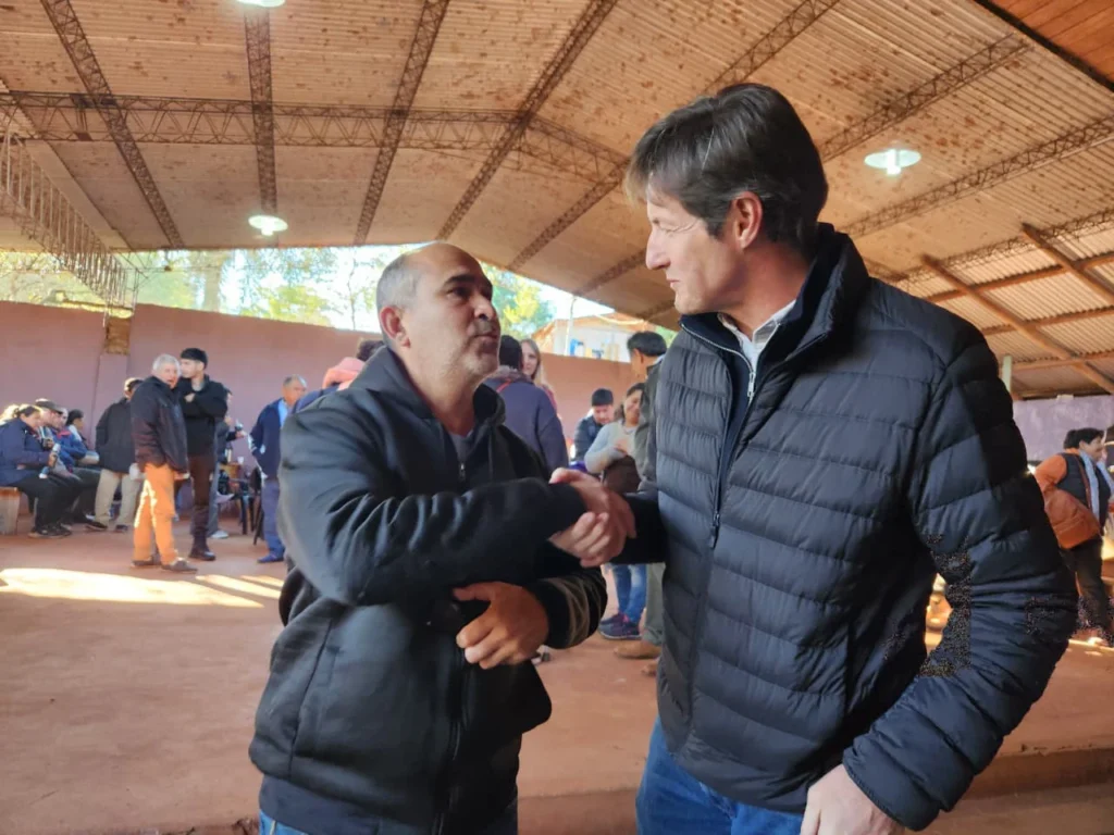 Héctor Decut y un vecino de Montecarlo se saludan con un apretón de manos.