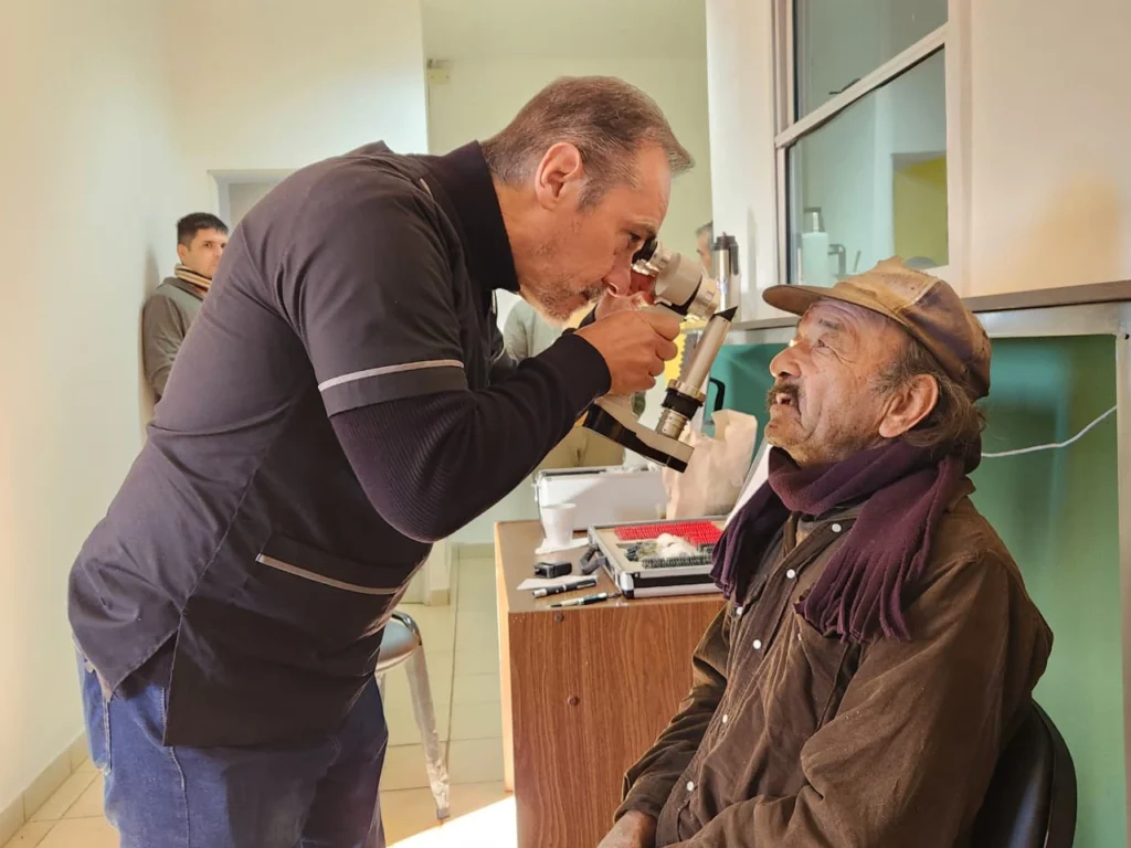 Oftalmólogo usa un tonómetro para medir la presión ocular de un vecino de Puerto Leoni.