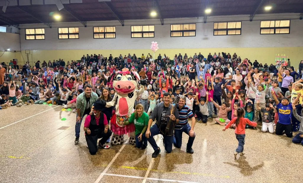 Foto grupal equipo de Gurises Felices y multitud de público infantil, en su visita a distintos municipio por el Mes de las Infancias.