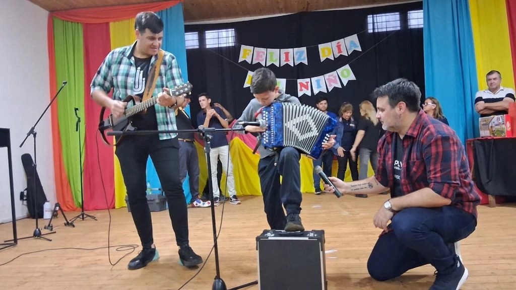 Nicolás Dlutowski toca su acordeón en el escenario, acompañado por el equipo de Gurises Felices.