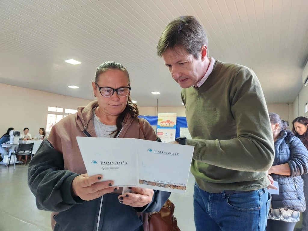Una vecina lee un texto de prueba con sus nuevos anteojos con la asistencia de Héctor Decut.