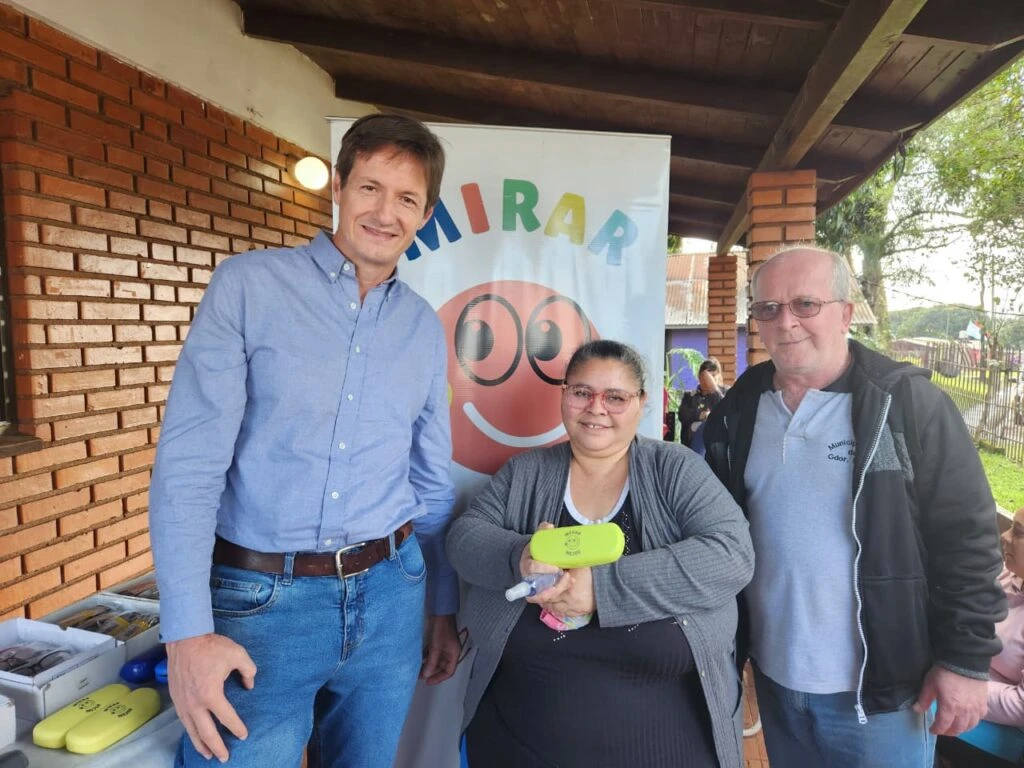 Vecina luce sonriente sus nuevoa anteojos de Mirar Mejor en Gobernador López, junto a Héctor Decut.