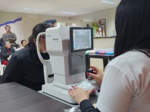 Oftalmóloga revisa los ojos de una vecina mediante un autorefractómetro. Dos años de Mirar Mejor en Olegario V. Andrade