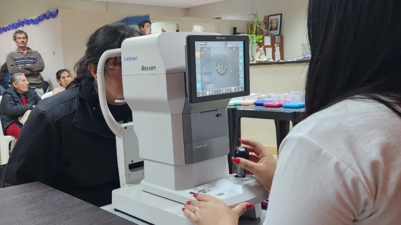 Oftalmóloga revisa los ojos de una vecina mediante un autorefractómetro. Dos años de Mirar Mejor en Olegario V. Andrade