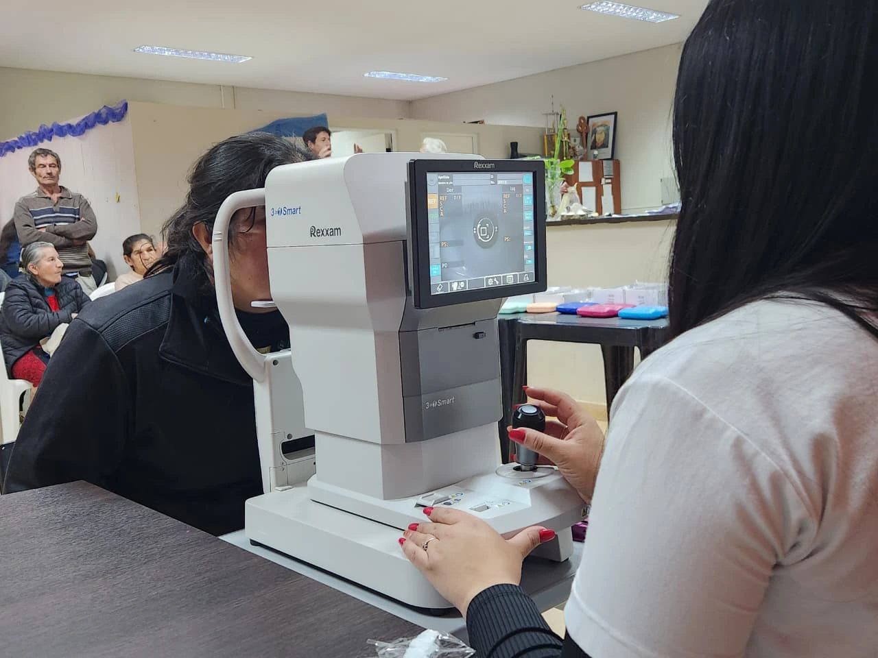 Oftalmóloga revisa los ojos de una vecina mediante un autorefractómetro. Dos años de Mirar Mejor en Olegario V. Andrade