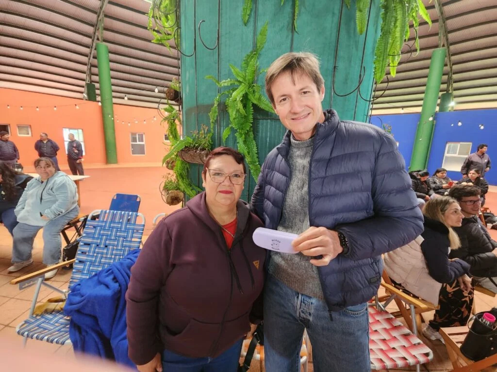 Vecina luce sonriente sus nuevos anteojos de Mirar Mejor junto a Héctor Decut.