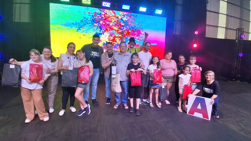 Niños felices con sus obsequios, acompañados sobre el escenario por sus padres y el equipo de Gurises Felices.