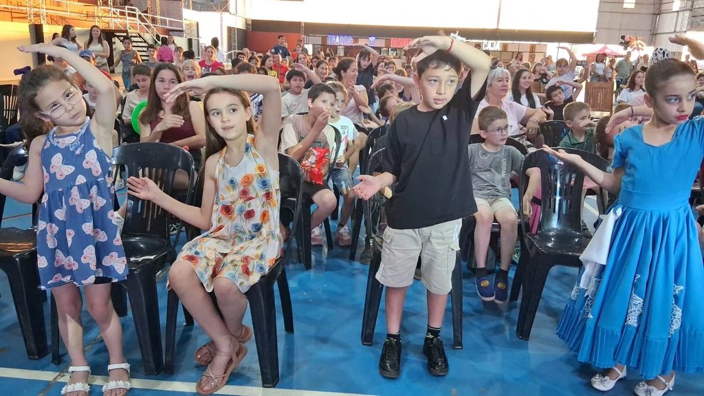 Público infantil acompaña las canciones de Gurises Felices con los brazos arriba.