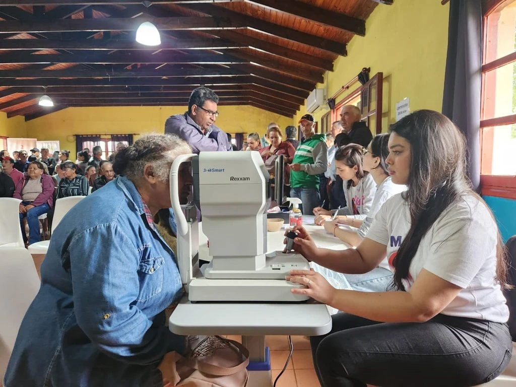 Oftalmóloga revisa los ojos de una vecina mayor mediante un autorefractómetro. Mirar Mejor en Alba Posse.