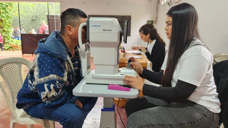 Oftalmóloga revisa los ojos de un joven vecino mediante un autorefractómetro. Mirar Mejor en Colona Polana.
